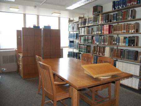 Room with tables, chairs, and bookshelves. Click on this picture to reserve this room.