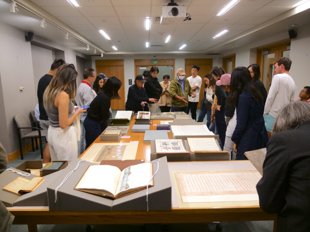 A library curator discussing rare Chinese books laid out on a table in the Rare and Manuscript Collection of Cornell University Library