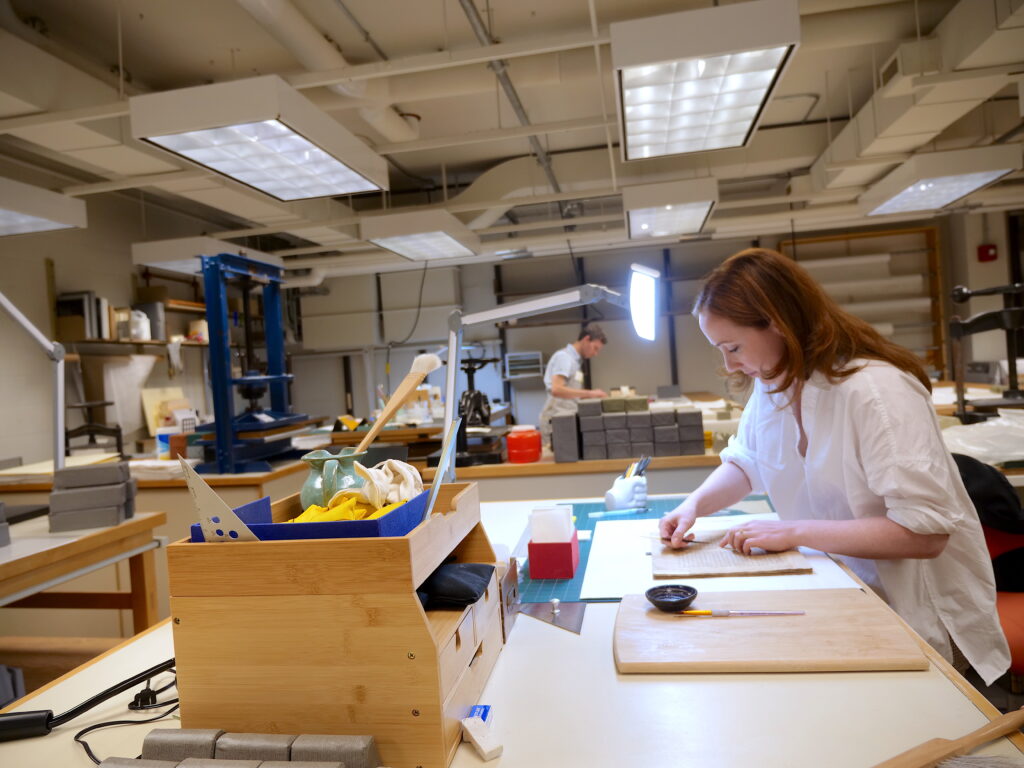 Two library conservators at the work desks at Cornell University Library's Conservation Lab.